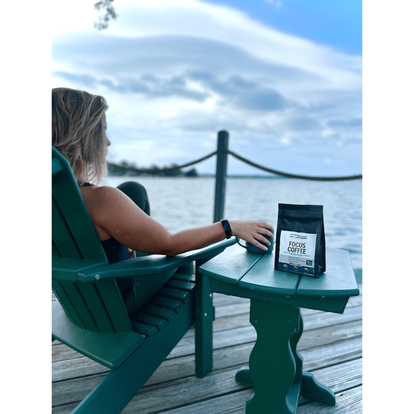 Woman drinking focus coffee by the lake on a summer morning